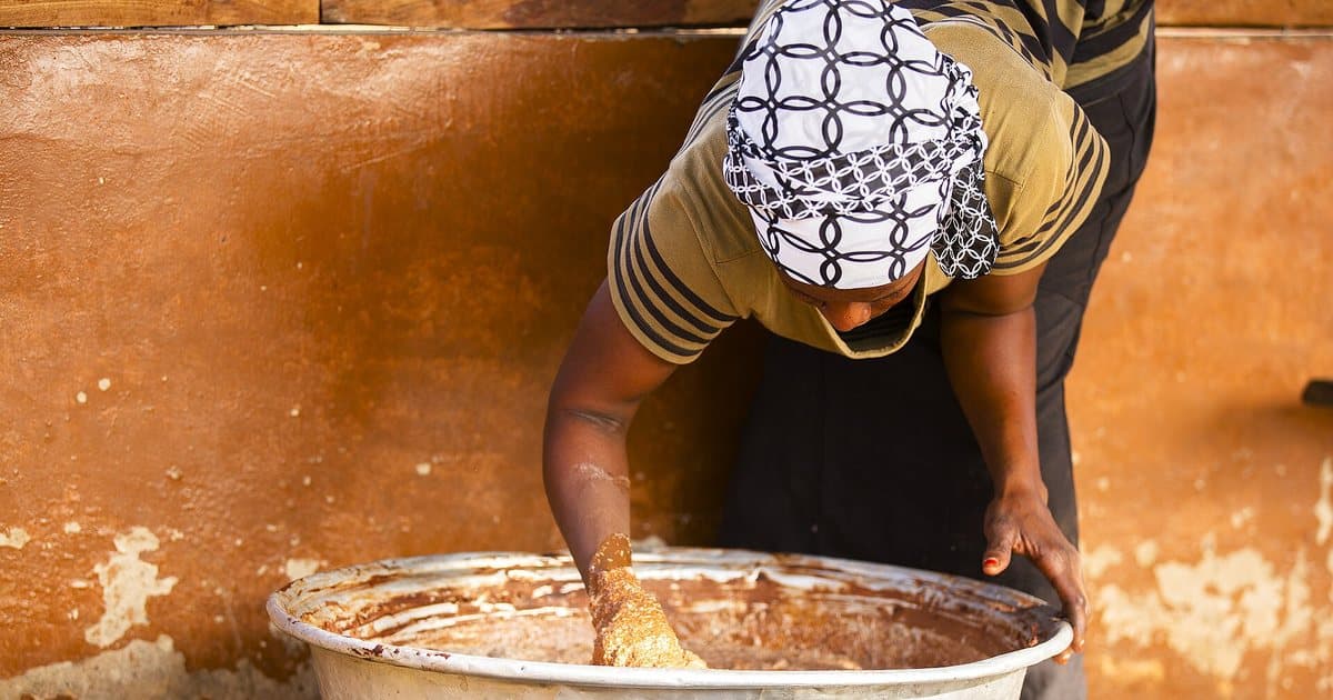 Woman kneading shea paste to extract the butter, Ghana